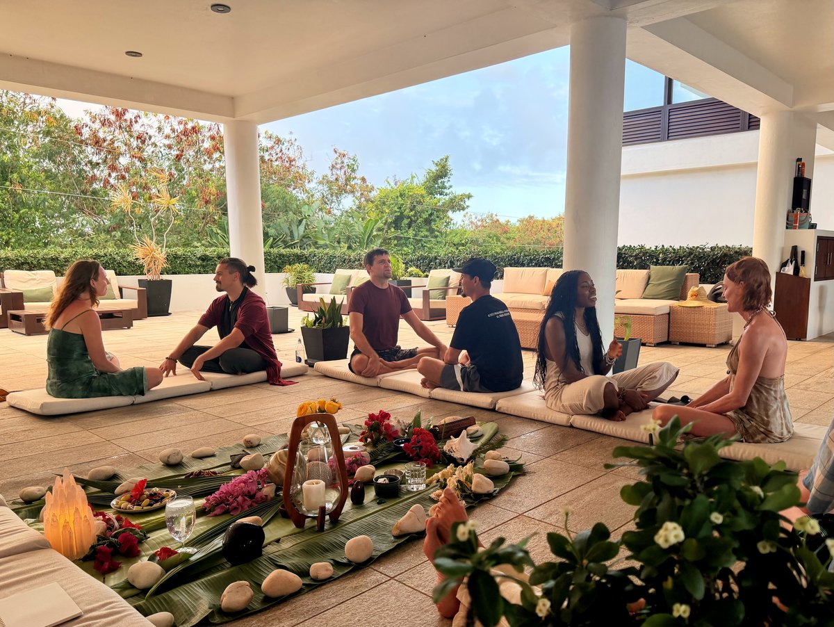 Participants seated in a circle on the open-air patio at Casa Cielo with a banana-leaf altar and candles in the foreground