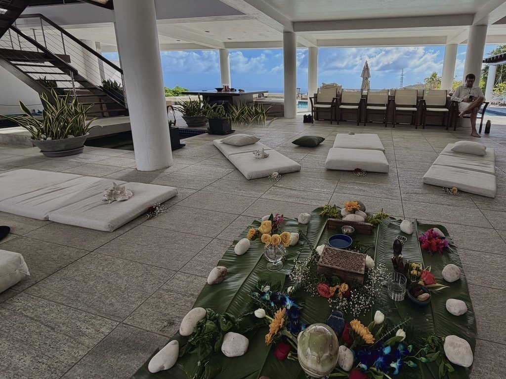 Banana-leaf altar at Casa Cielo with stones, flowers, and ocean view beyond